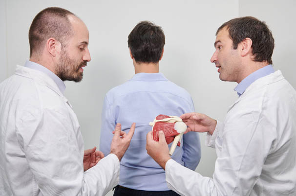medico ortopedico che spiega la struttura della spalla a un paziente con un modellino plastico